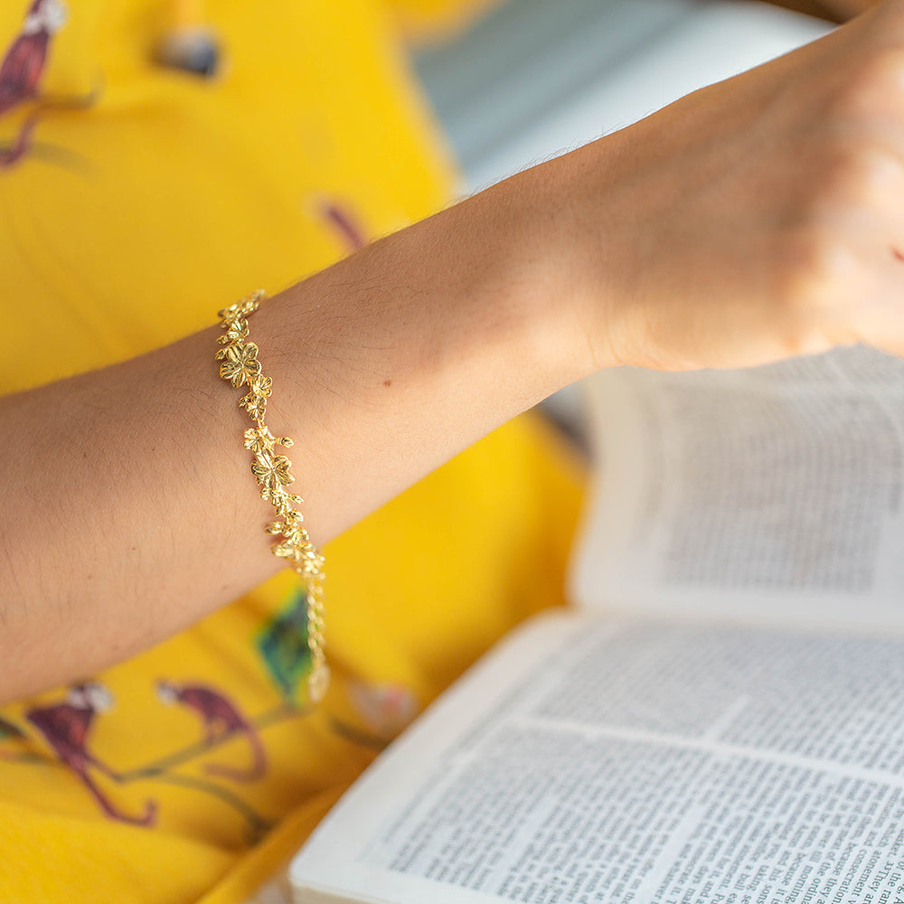 Mulher usando a Pulseira Cristã Ester 22L em Prata de Lei com banho de ouro 18kt enquanto lê a Bíblia em seu colo